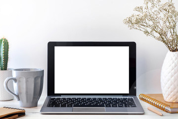 Fototapeta premium Hipster wooden desk with an open laptop mockup, a white vase with dried flowers, a notebook, a notebook, a gray cup of coffee and a cactus
