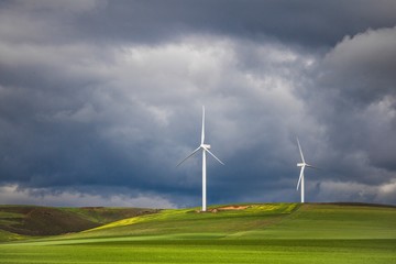 Dramatic thunderstorm over wind turbines in green fields - Caledon, Western Cape, South Africa.