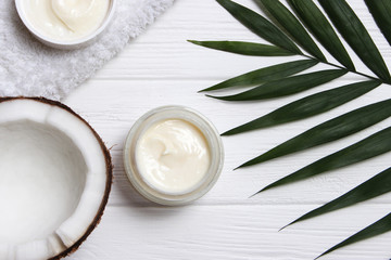 Tropical leaf, care cosmetics and coconut on a wooden table. Top view. Means for hair, body, skin. flatlay