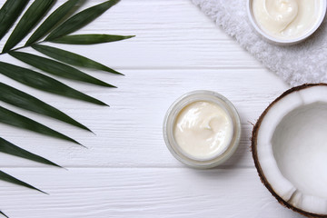 Cosmetic natural skin care products from coconut. palm leaf, coconut and cosmetic cream on a wooden background. minimalism, the top. flatlay 
