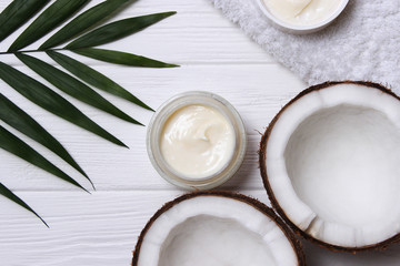 Fototapeta na wymiar Cosmetic natural skin care products from coconut. palm leaf, coconut and cosmetic cream on a wooden background. minimalism, the top. flatlay 