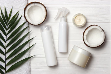 Tropical leaf, care cosmetics and coconut on a wooden table. Top view. Means for hair, body, skin. flatlay