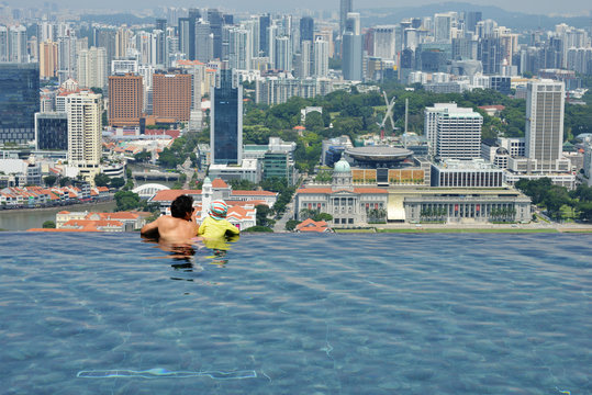 Father and son having fun at infinity pool in summer holiday 
