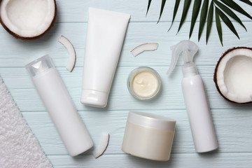 Tropical leaf, care cosmetics and coconut on a wooden table. Top view. Means for hair, body, skin. flatlay