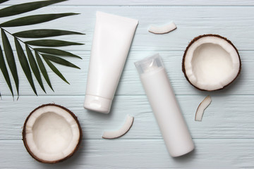 Fototapeta na wymiar Tropical leaf, care cosmetics and coconut on a wooden table. Top view. Means for hair, body, skin. flatlay