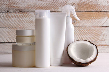  set of cosmetics and coconut half on a wooden background. Coconut-based hair, body and skin care products.