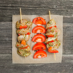 Making kebabs from chicken - raw meat on skewers on plate on aged wooden background. Selective focus. Rustic style. Place for text.