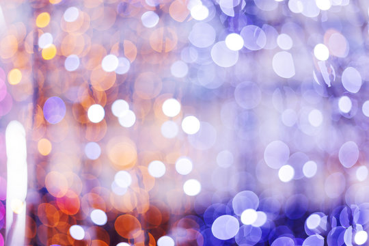 Defocused night street lights, blurred colorful bokeh background. Holiday colorful lanterns and light bulbs garlands.