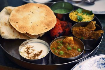 Assorted Indian food set in tray, tanduri chicken, naan bread, yoghurt, traditional curry, roti
