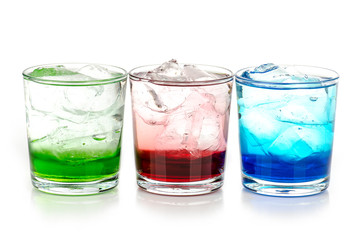 green, blue and red drink with ice cubes on white background