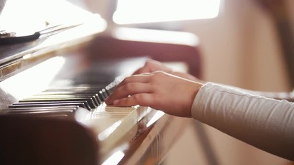 Child opening and playing piano. Close up on piano keys, child hands and fingers.
