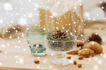 christmas and winter concept - decoration of fir twig with pinecone in ice cream glass or dessert bowl over snow