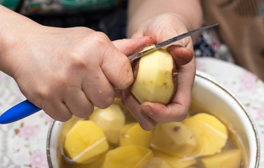The cook cleans the potatoes with a knife