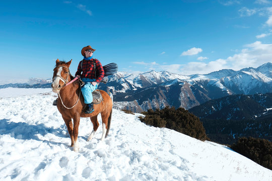 Extreme Snowboarder. Free Rider A Man In A Cowboy Hat Riding A Horse In The Snow. Winter. The Mountains.