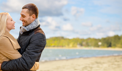 love, relationships and people concept - happy couple hugging over autumn beach background