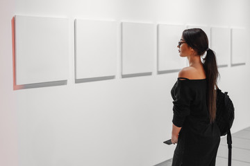 Close up of woman looking at blank canvas posters on the wall in art gallery.
