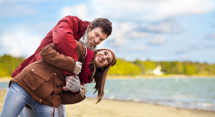 love, relationships and people concept - happy teenage couple having fun over autumn beach background