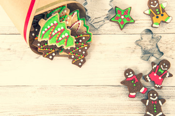 Obraz premium Beautiful Christmas composition and decoration with baked Christmas gingerbread cookies in paper bag on light wooden background, flat lay, top view, copy space (text space)