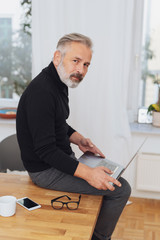 Pensive businessman perched on his desk