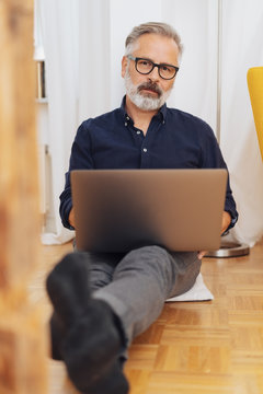Middle-aged man sitting on floor with laptop