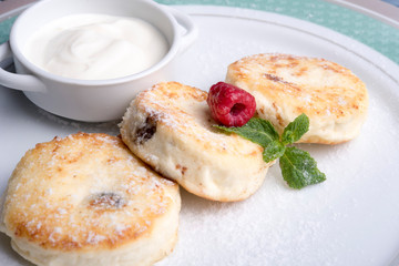 traditional russian or ukrainian breakfast syrniki - cottage cheese pancakes with honey and sour cream and raspberries