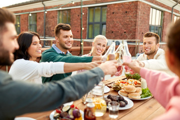 leisure and people concept - happy friends toasting drinks at rooftop party in summer