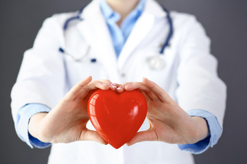 Female doctor with stethoscope holding heart in her arms. Healthcare and cardiology concept  in medicine 