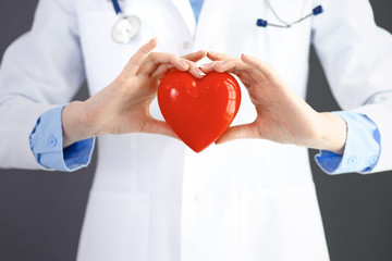 Female doctor with stethoscope holding heart in her arms. Healthcare and cardiology concept  in medicine 