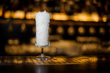 Cocktail glass for Sherry Cobbler filled with ice on the bar counter