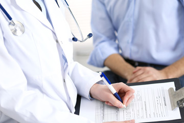 Fototapeta premium Female doctor holding application form while consulting man patient in hospital. Medicine and healthcare concept