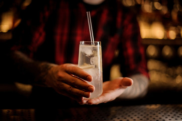 Bartender holding elegant long drink glass filled with Tom Collins cocktail