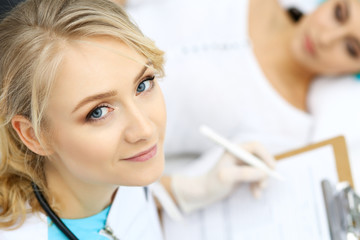 Obraz premium Female doctor and young woman patient in hospital. Physicians examine girl lying at the bed, view from above