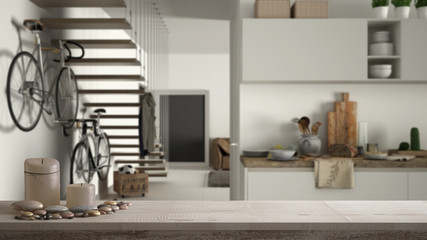 Wooden vintage table top or shelf with candles and pebbles, zen mood, over blurred contemporary white kitchen, minimal architecture interior design
