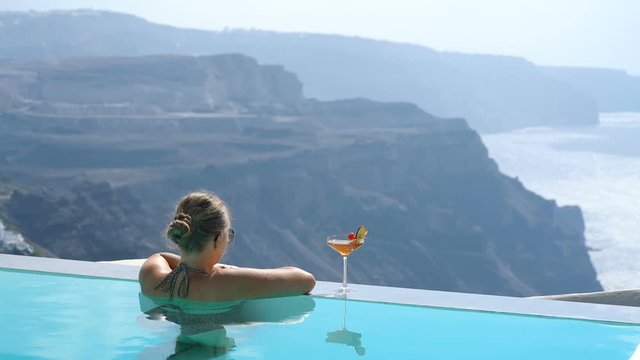 Young woman relaxing in the pool with a gorgeous view on Santorini
