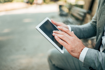 Close-up image of businessman using tablet outdoors.