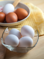 white and brown eggs on a wooden table, a towel and a wooden spoon
