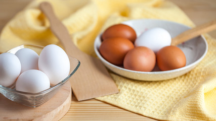 white and brown eggs on a wooden table, a towel and a wooden spoon