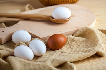 white and brown eggs on a wooden table, a towel and a wooden spoon