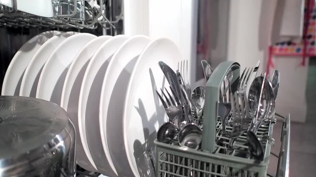 Open dishwasher with clean dishes in the white kitchen