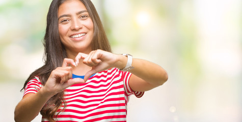 Fototapeta premium Young beautiful arab woman over isolated background smiling in love showing heart symbol and shape with hands. Romantic concept.