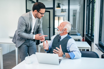 Senior and young man discussing at work.