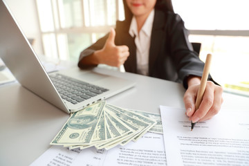 businesswoman signing contract and showing thumb up with money