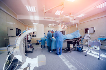 Process of trauma surgery operation. Group of surgeons in operating room with surgery equipment.