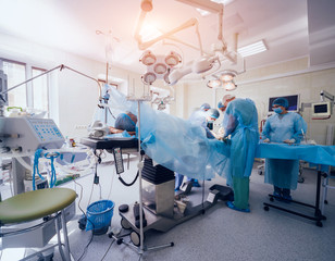 Process of trauma surgery operation. Group of surgeons in operating room with surgery equipment.