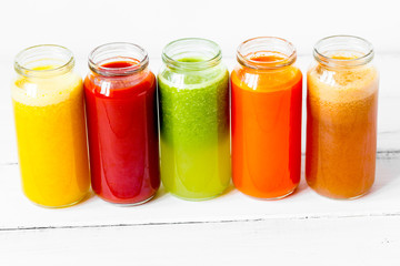 Fresh detox juices glass in row bottles on white background