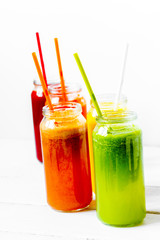 Fresh detox juices glass in row bottles on white background