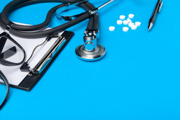 Stethoscope, clipboard and pills, closeup. Medical equipment