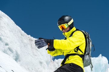 Fototapeta na wymiar Professional skier in a helmet with a backpack and a ski mask standing on a glacier is preparing to jump wearing membrane gloves. The concept of quality training for the sport