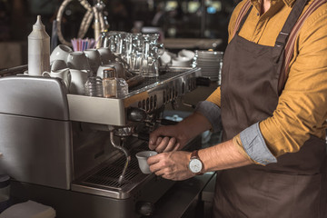 cropped shot of professional barista preparing coffee with coffee machine in cafe