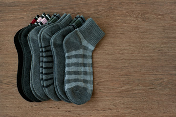 A set of socks for autumn and winter. View from above. Gray and black socks are warm footwear for the fall and winter seasons. Stylish classic socks on wooden background.